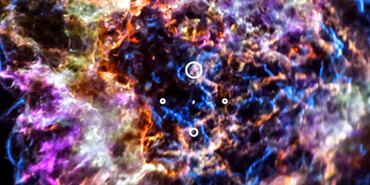 Cassiopeia A resembles a disk of electric light with red clouds, glowing white streaks, red and orange flames, and an area near the center of the remnant resembling a somewhat circular region of green lightning. X-rays from Chandra are blue and reveal hot gas, mostly from supernova debris from the destroyed star. X-rays are also present as thin arcs in the outer regions of the remnant. Infrared data from Webb is red, green, and blue. Hubble data shows a multitude of stars that permeate the field of view.