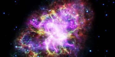 Combined telescope images of the Crab Nebula displayed in red, yellow, green, ultraviolet, and X-ray light.