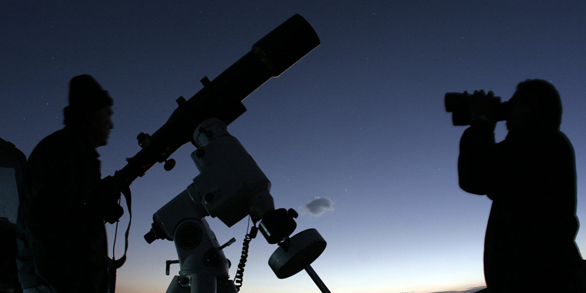 Image of a person in shadow at night getting ready to observe transiting exoplanets with a telescope that appears to be slightly larger than his frame.