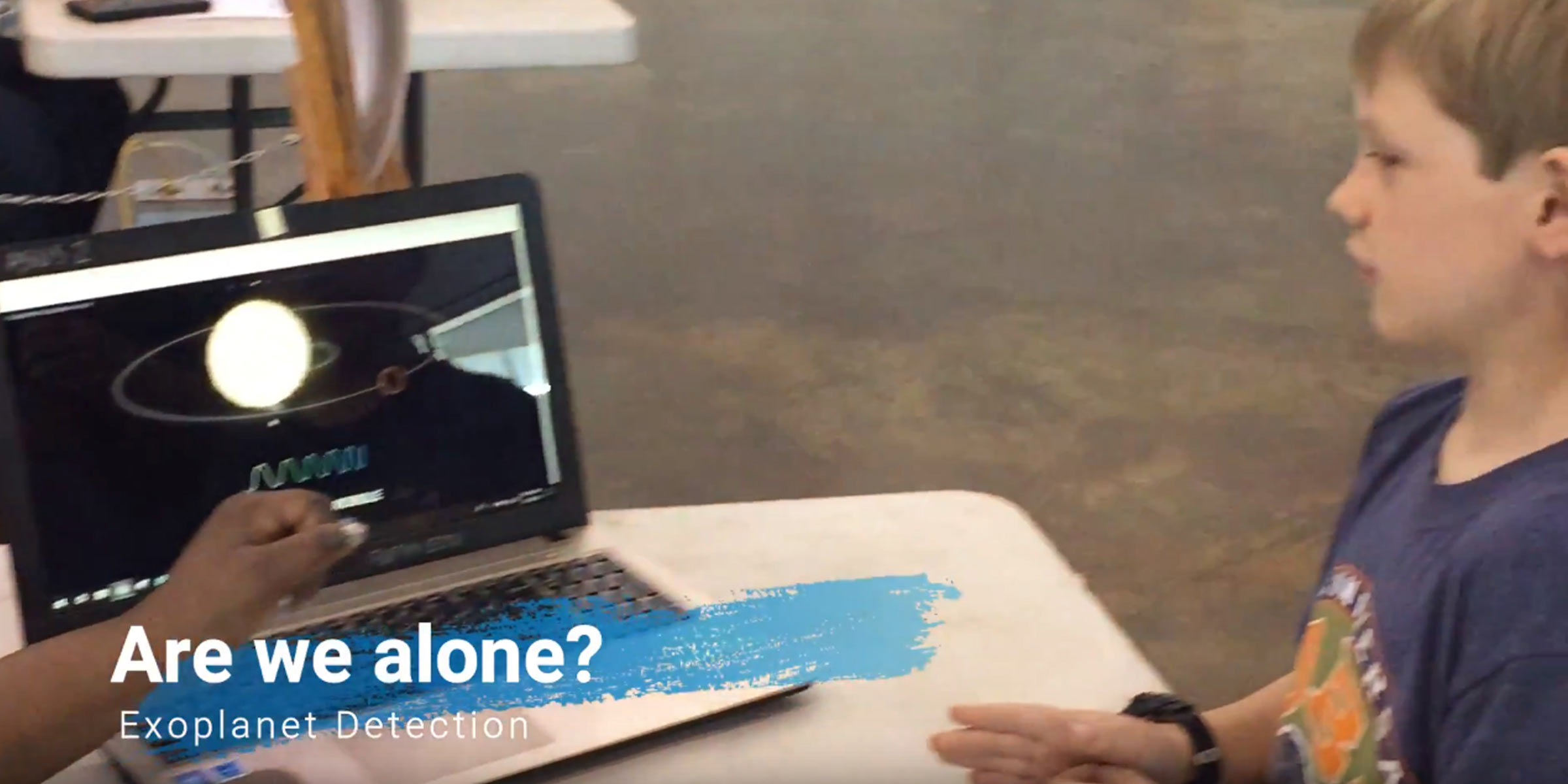 Child at computer with "Are we Alone?" on the lower third