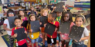 Several children proudly holding up their art work