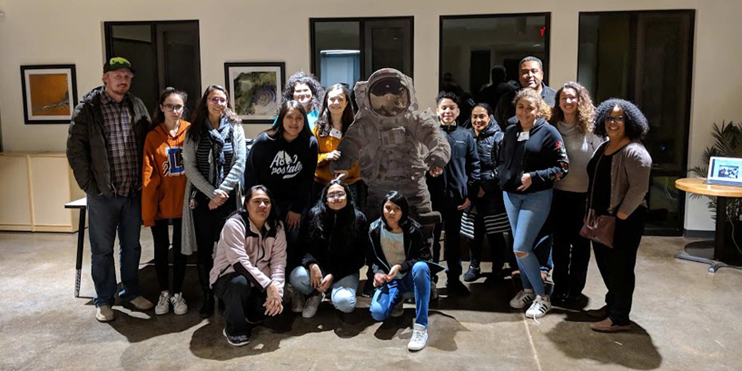 Group of teenagers posing together with a life-size astronaut cut out