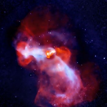M87 as seen by the Very Large Array and Chandra X-ray Observatory. Against the black background of space is an orange blob in the center, roughly shaped like a light bulb on its side. The interior of the orange bulb is brighter, with shades of yellow and white. Two streams of blue-white hot gas extend from the orange bulb-shaped center, one stream reaching horizontally toward the left and the other diagonally stretching toward the lower right corner. Cloudy red-orange material is dispersed unevenly around the orange blob. The red-orange material is heaviest in the top left and lower right corners. Small, fuzzy blue-white dots are scattered across the background.
