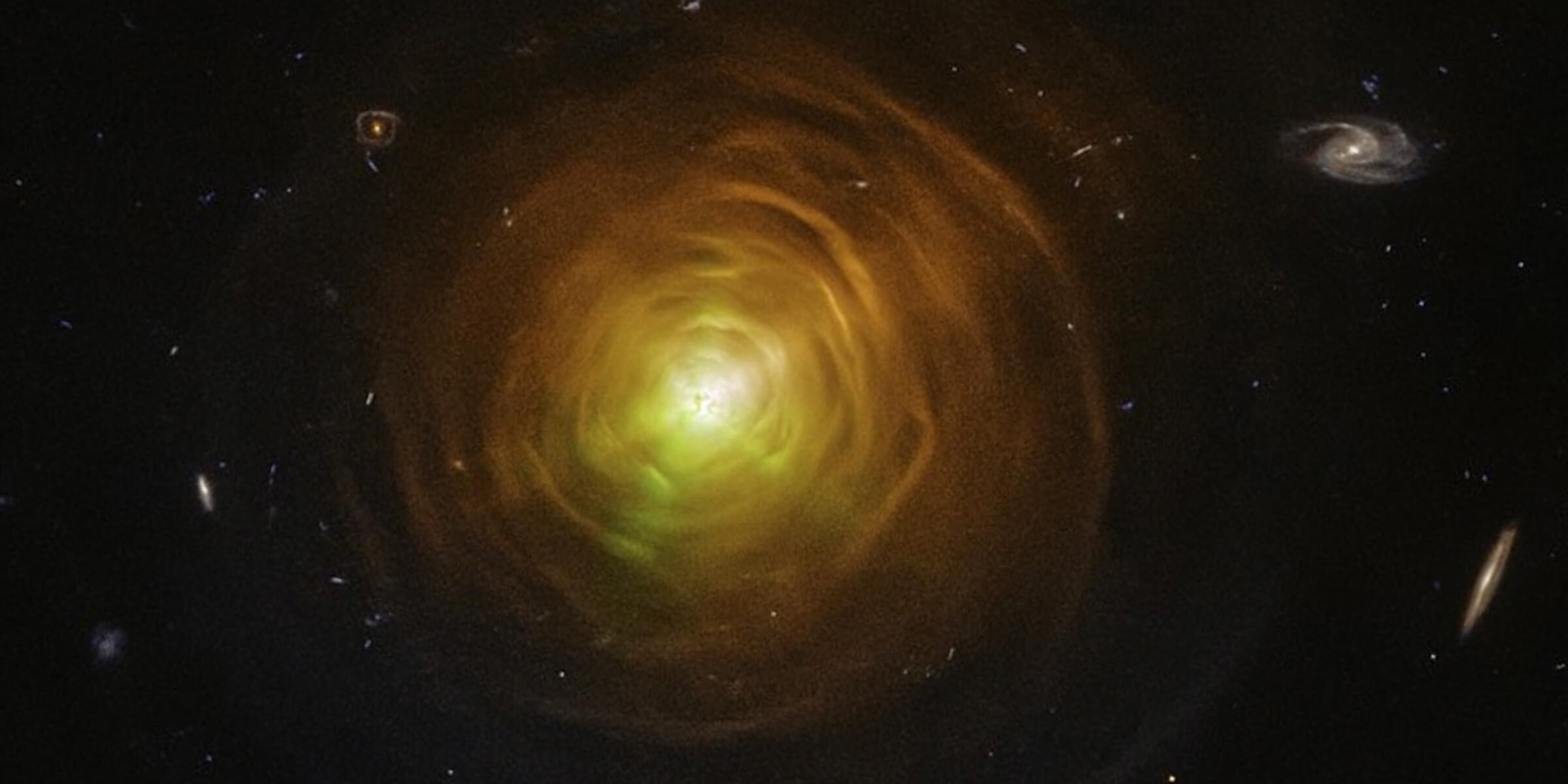 Red-orange arcs surround the carbon star CW Leonis. Brilliant searchlight beams from the star’s surface poke through.