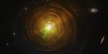 Red-orange arcs surround the carbon star CW Leonis. Brilliant searchlight beams from the star’s surface poke through.