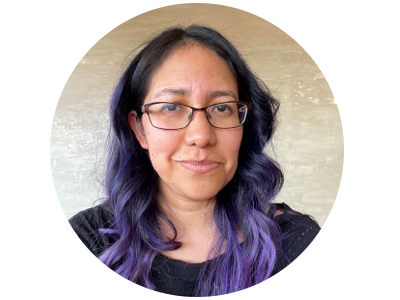 A woman with purple hair and glasses smiling at the camera.