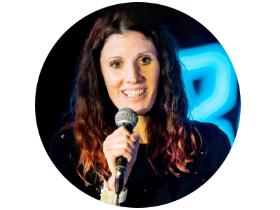 A women with long dark red hair holding a microphone