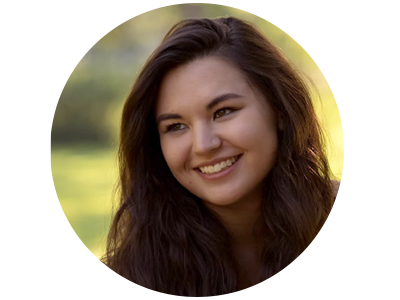 A woman with long dark hair on a sunlight background smiles to the left of the camera.