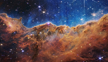 Image of bright eight-pointed stars scattered across a dense orange-brown undulating cloudscape below a deep blue starscape.